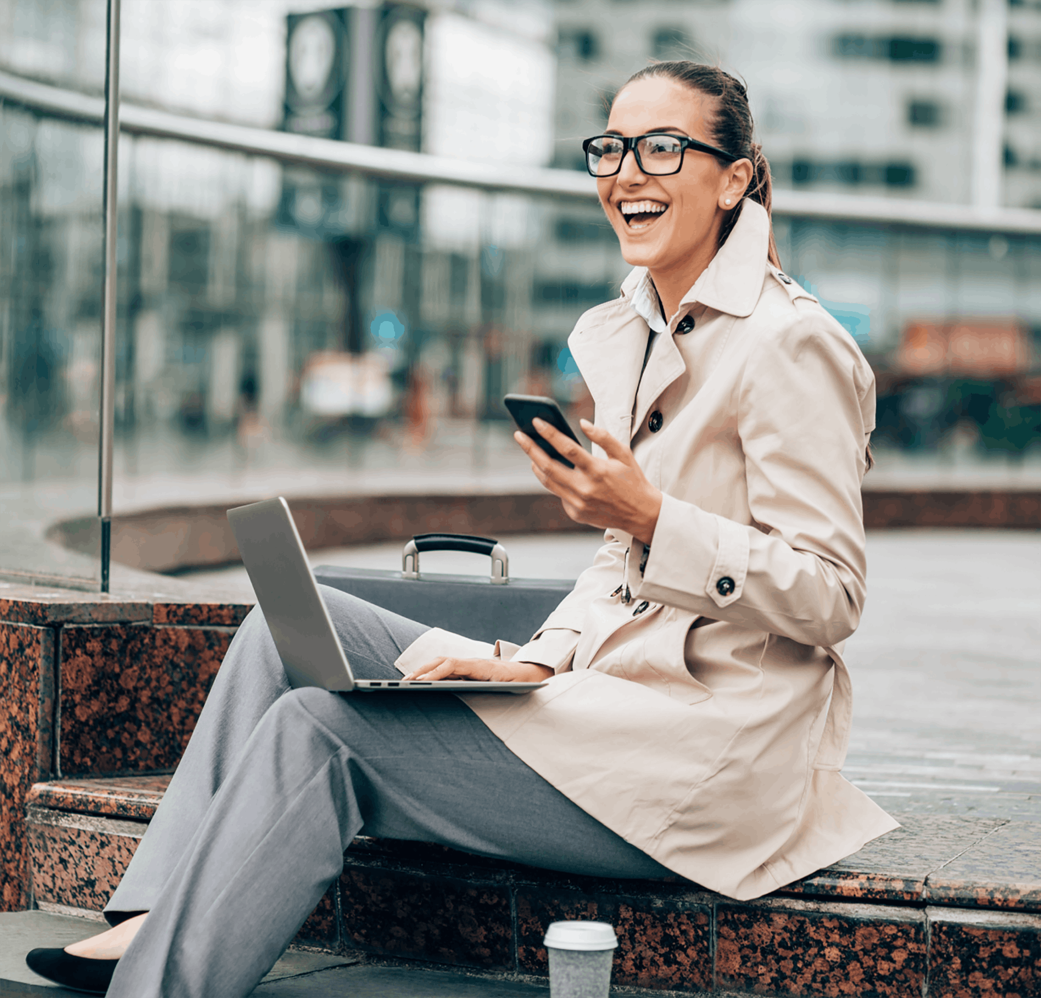 Woman using phone outside on laptop sitting