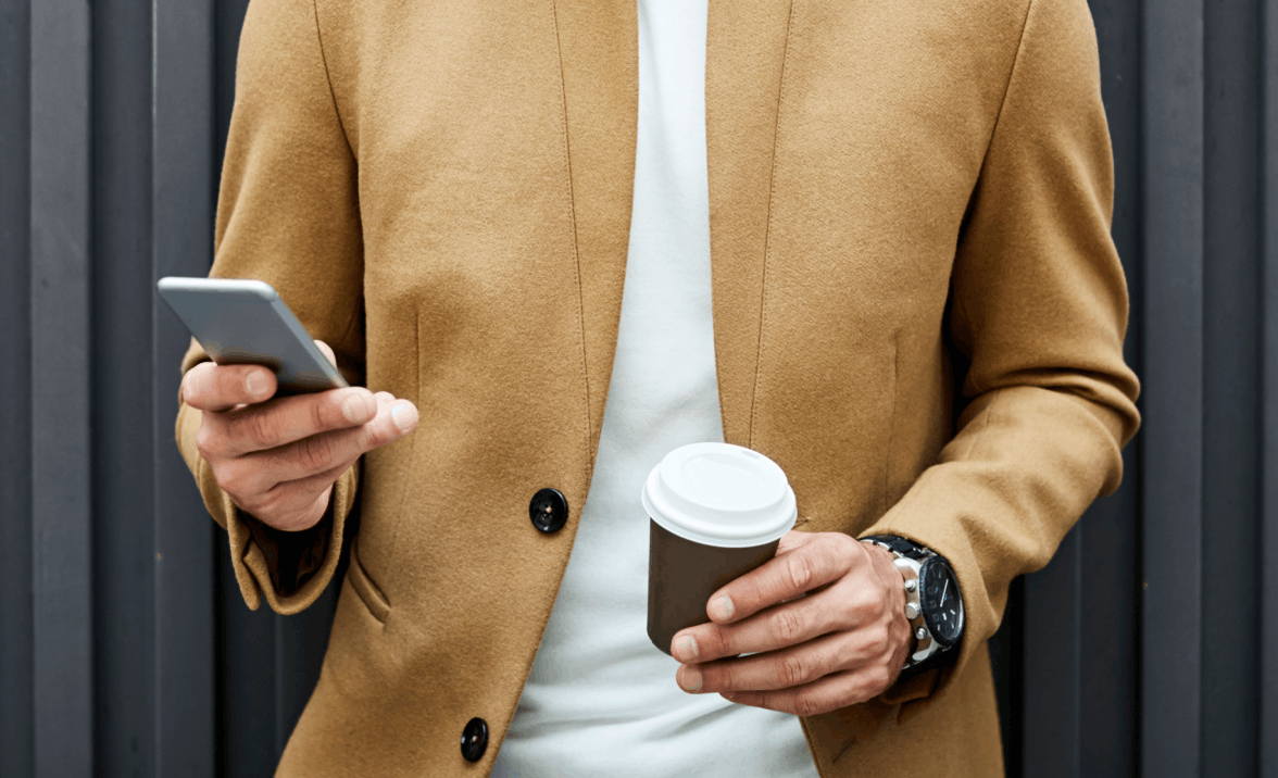 man holding phone and coffee